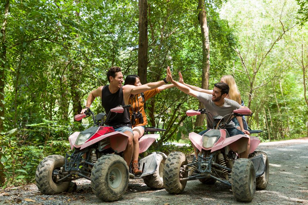 A group of friends riding ATVs on road along forest trail