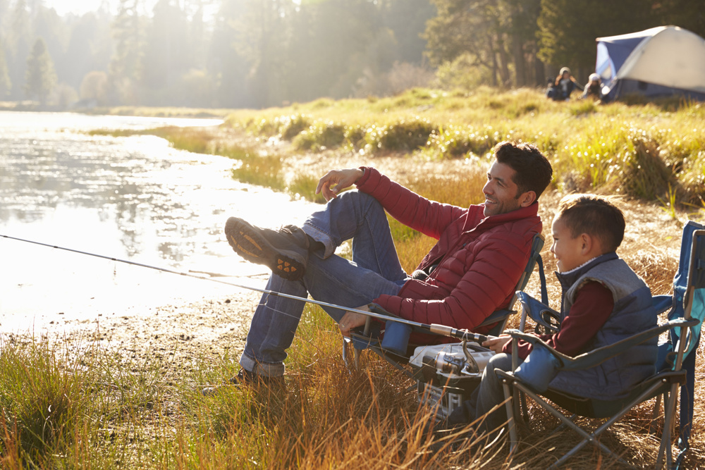 Father and son on a camping trip fishing by a lake