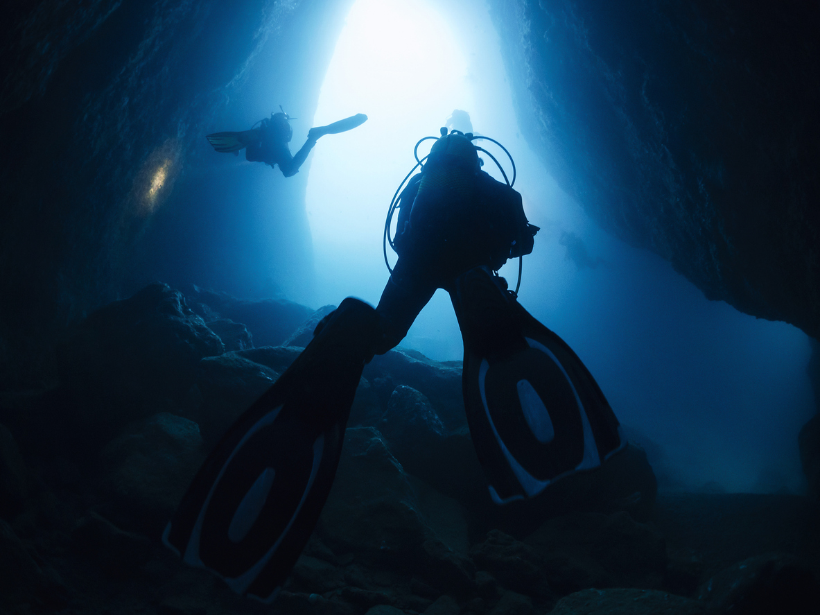 Diving between the rocks of an underwater cave