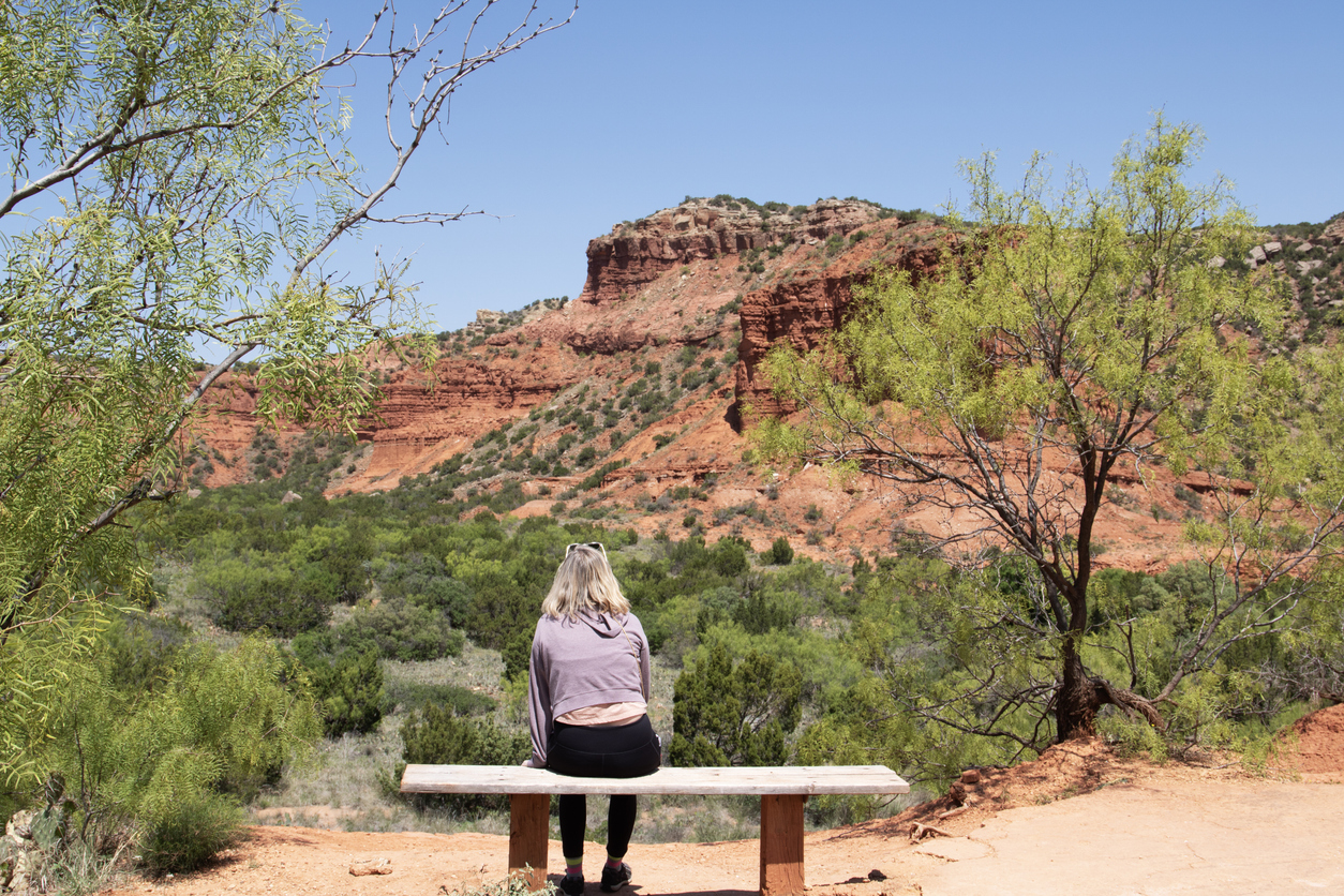 girl on bench overlooking a canyon