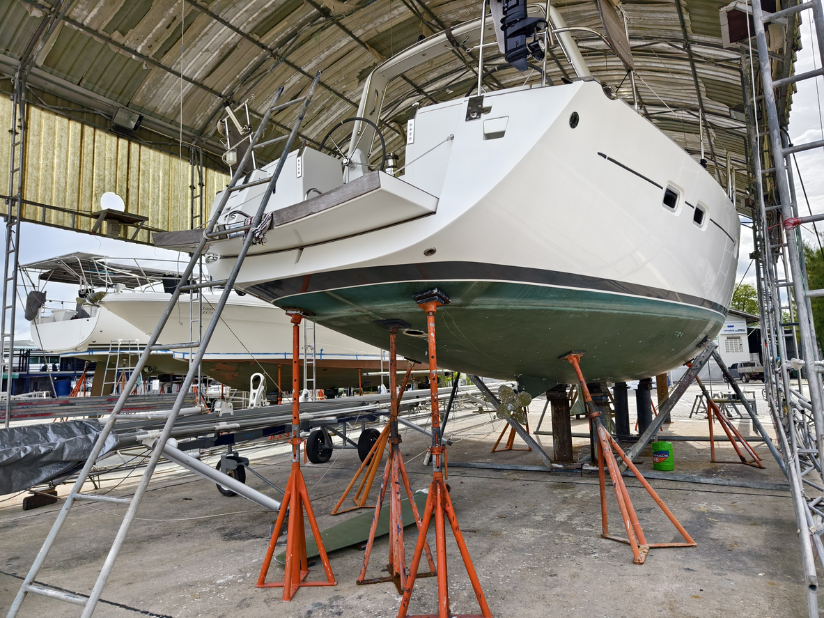 A boat is carefully lifted under a covered structure