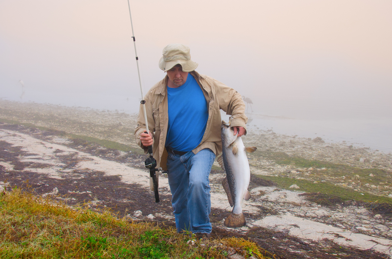 Fisherman with a huge fish he caught on a foggy morning