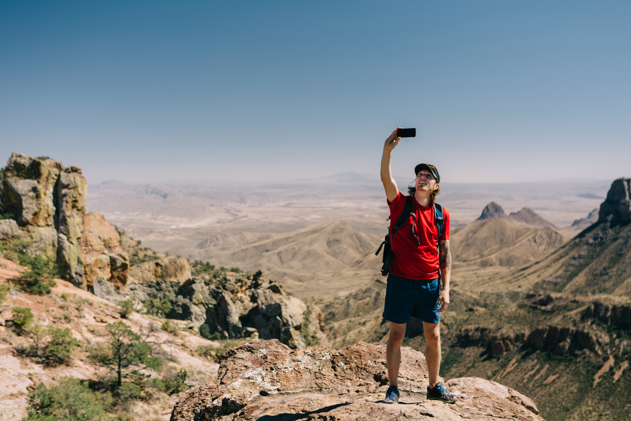 Man taking photo of mountain view with smart phone