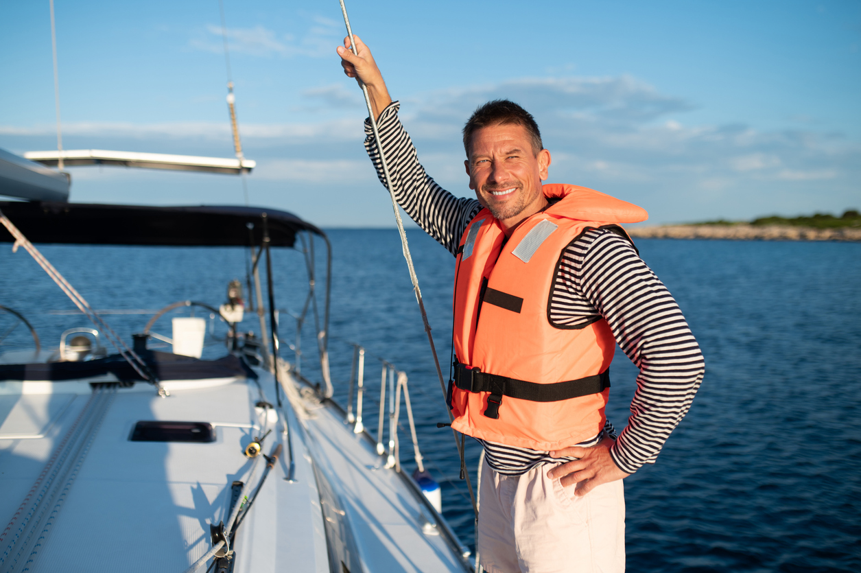 Mature man in a life jacket on a yach feeling good