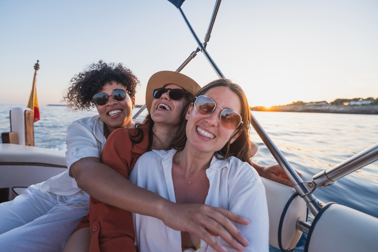 Three women enjoying sunset together on a boat