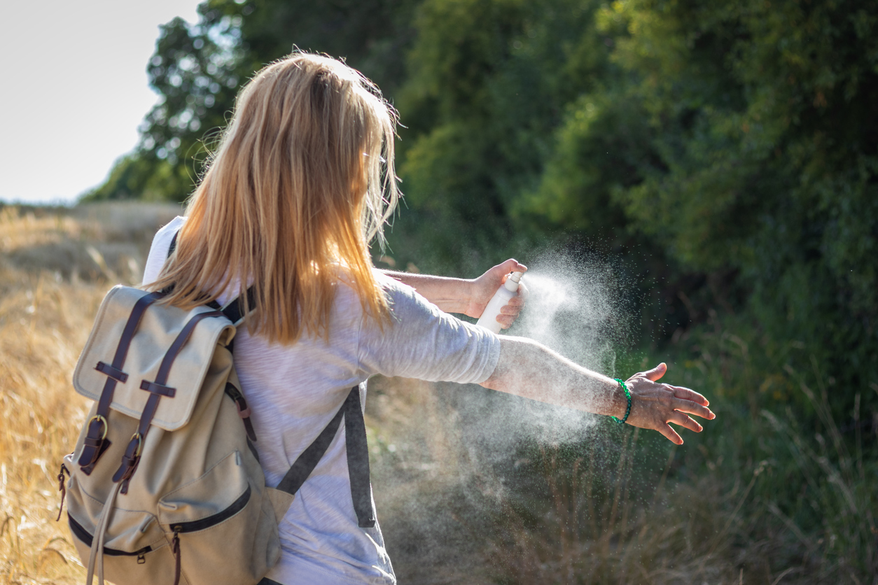 Woman tourist applying mosquito repellent on hand during hike in nature. Insect repellent