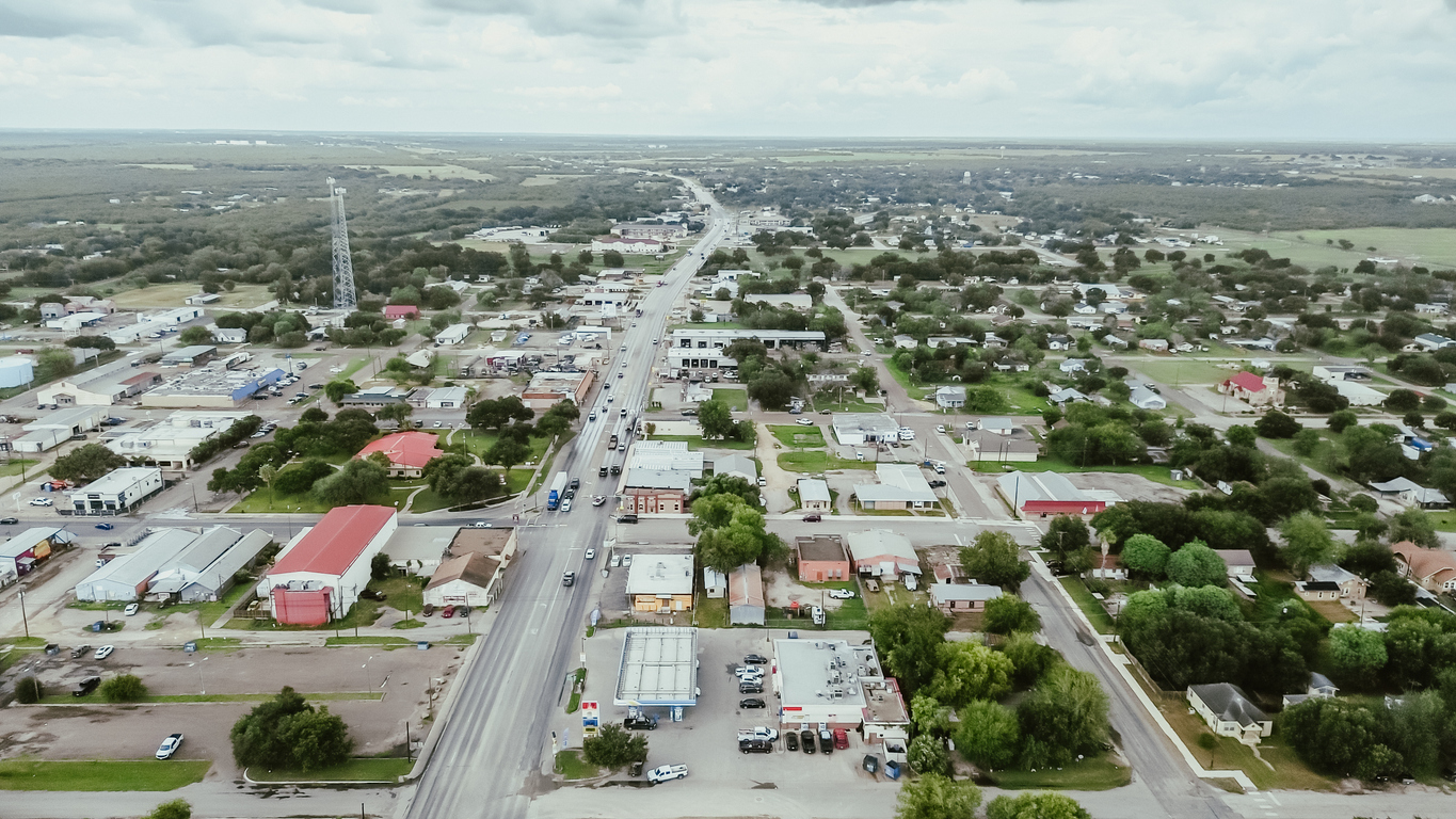 Small town Three Rivers South of San Antonio along U.S. Highway 281, Texas, mix of industrial, business buildings and residential houses farmland, suburban rural scene, lush green trees, aerial. USA