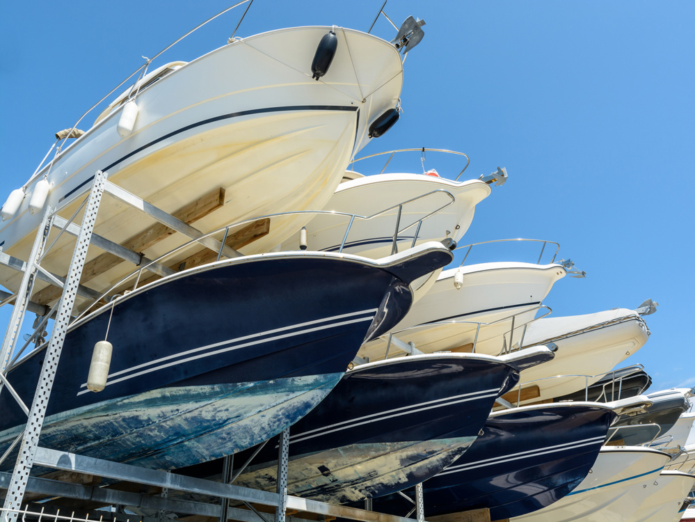 View from below of the hulls of motorboats racked one above another on two levels in a dry rack boat storage facility