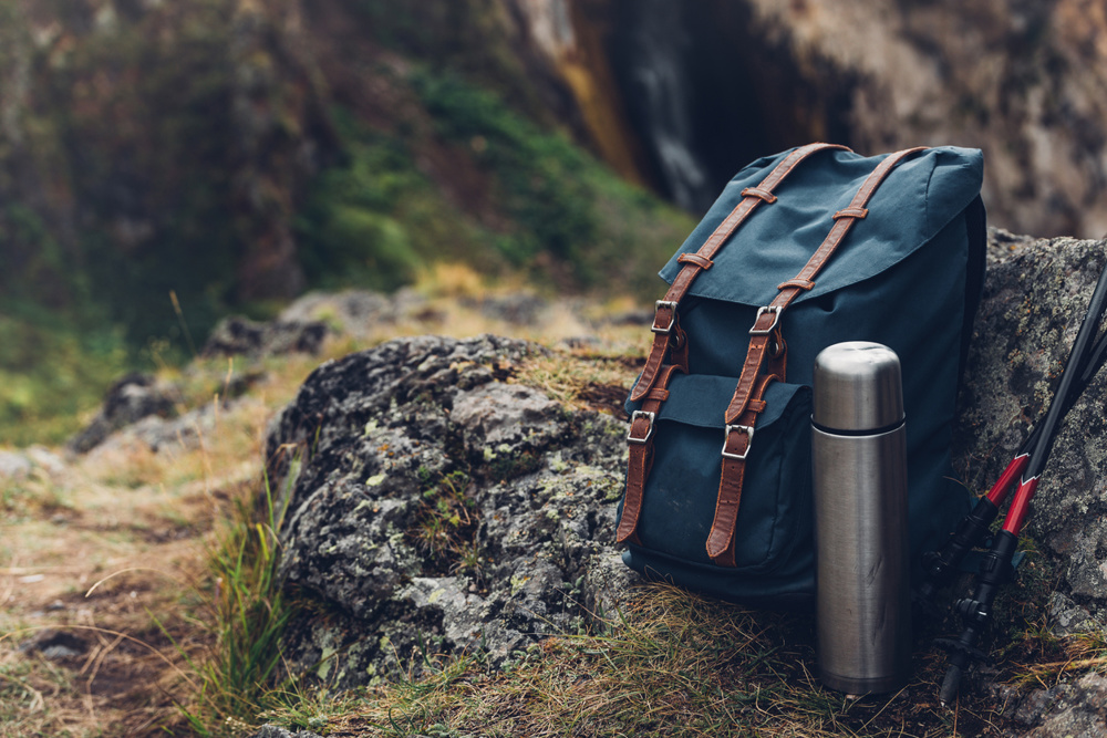 Blue hiking backpack, a thermos and trekking sticks